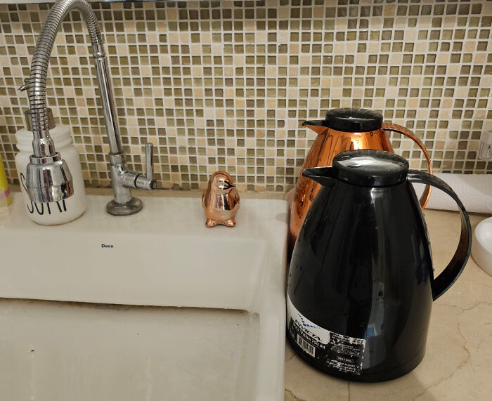 Two insulated coffee pots by a kitchen sink with a soap dispenser and tiled backsplash, capturing wholesome mom moments.