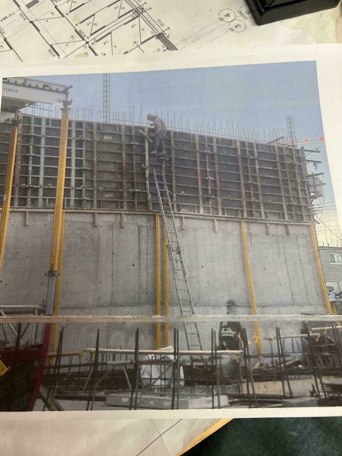 Construction worker climbing a tall ladder on an unfinished concrete wall in unsettling and creepy job site photo