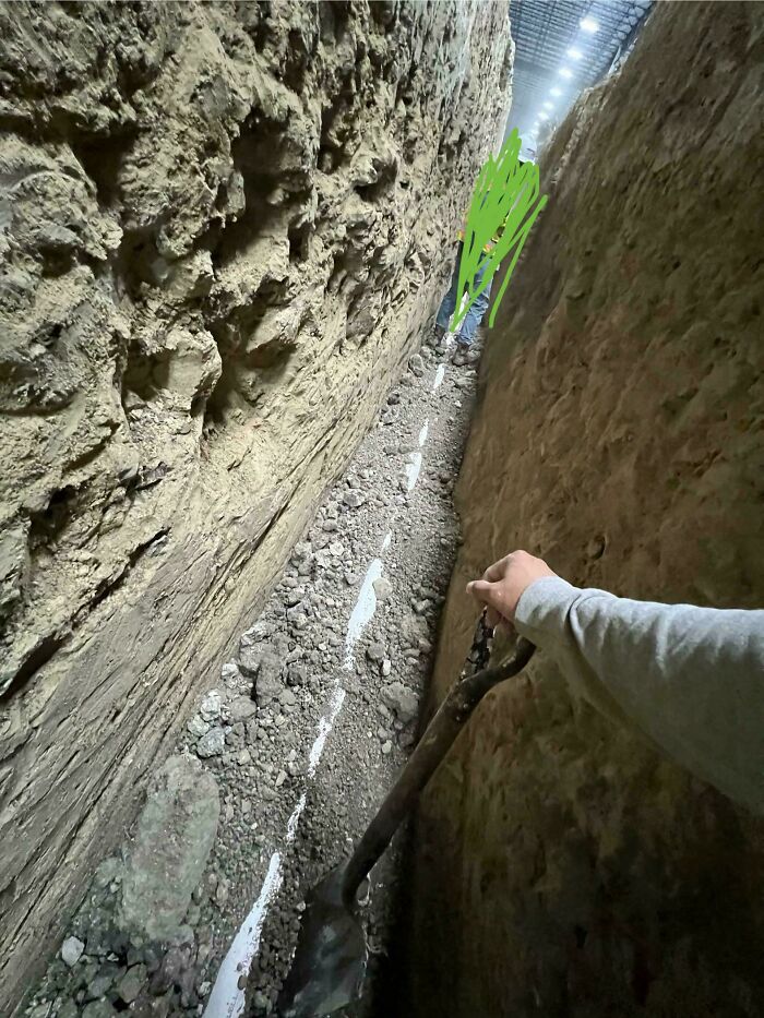 Worker digging a narrow trench between two walls, illustrating one of the jobs that should pay more from unsettling photos.