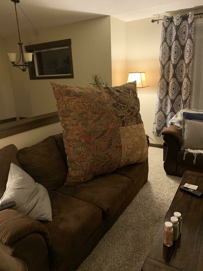 Large patterned pillow on a brown couch in a cozy living room, capturing wholesome mom moments and happiness.