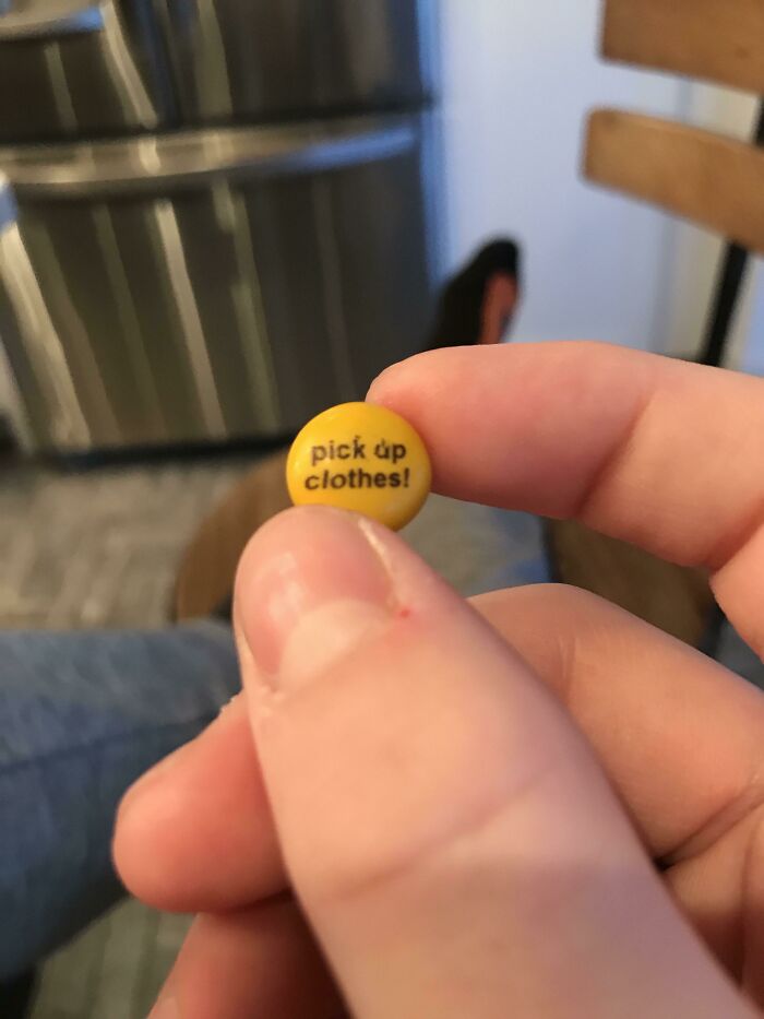 Close-up of a person holding a yellow candy with the message pick up clothes, capturing wholesome mom moments.