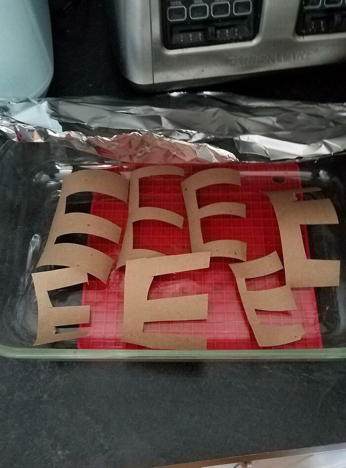Cardboard pieces arranged in a baking dish humorously resembling the shape of stools, showing funniest parents' creativity.