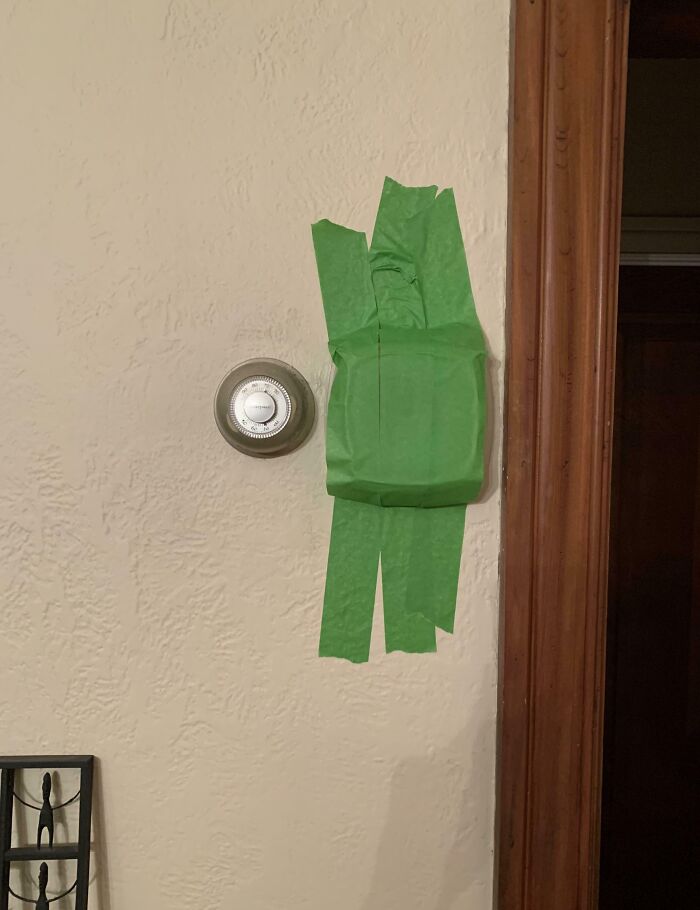 Thermostat covered with green tape shaped like a character, showcasing one of the funniest parents' creative pranks.
