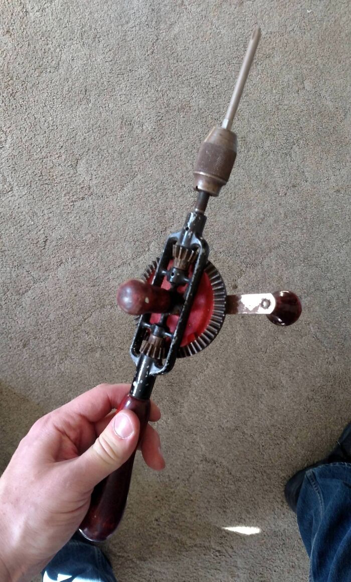 Hand holding a vintage manual hand drill, showcasing a classic tool from funniest parents ever collection.