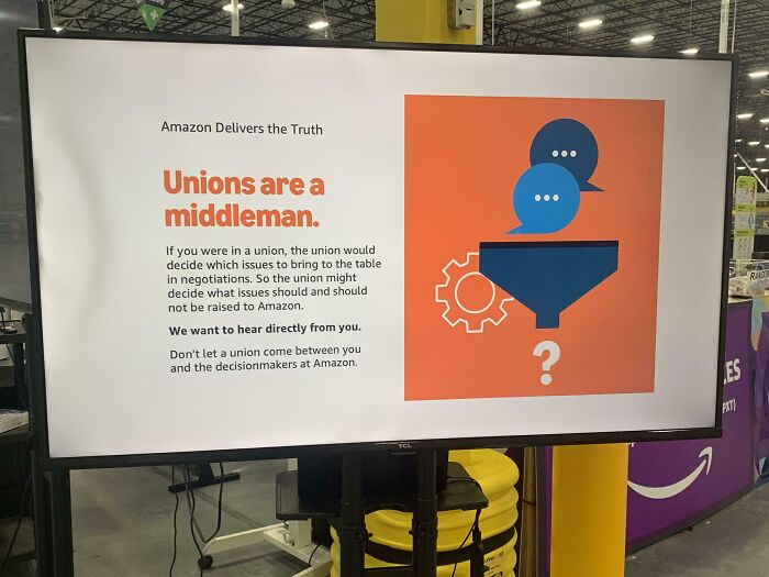Sign in an Amazon warehouse stating unions are a middleman, with text discouraging union involvement at the company.