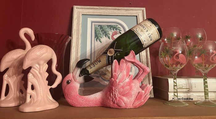 Pink flamingo bottle holder pouring champagne, surrounded by flamingo-themed glasses and decor showcasing funny and wholesome parents.