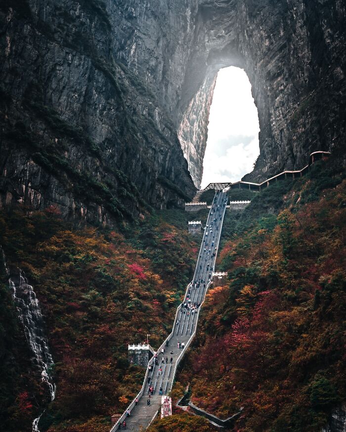 Stairway through a natural rock arch with visitors, showcasing captivating everyday life glimpses in Asia photography.