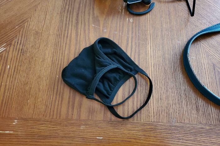 Black face mask lying on a wooden table, part of funny and wholesome moments parents shared with their kids.