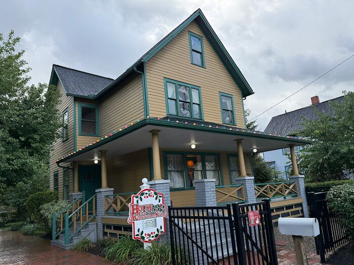 Yellow Victorian TV house with green trim and holiday lights, one of the iconic TV houses that exist in real life.