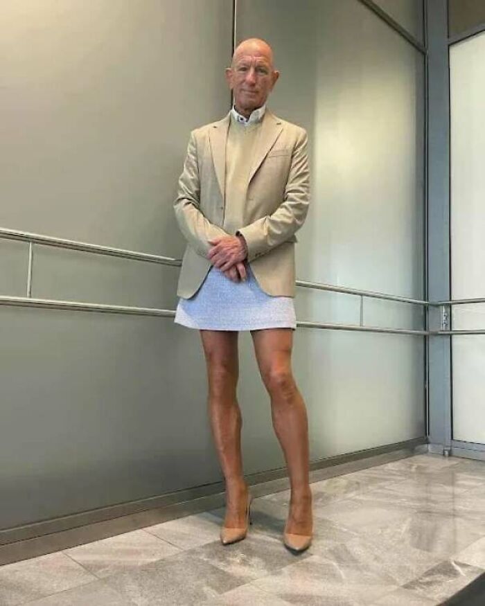 Older man wearing blazer and skirt standing confidently indoors, embodying inspiring facts and bold self-expression.
