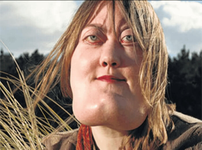 Close-up of a woman outdoors, smiling gently with windblown hair, illustrating inspiring facts better than watching the news.
