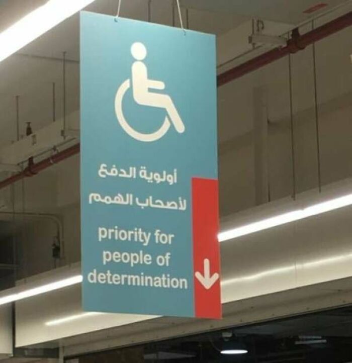 Sign with a wheelchair symbol and text showing priority for people of determination in a public indoor space.