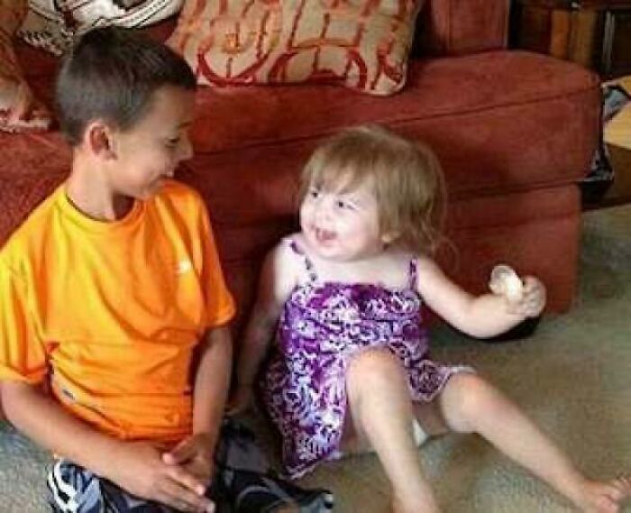 Two children sitting on the floor, smiling and interacting, capturing a joyful moment better than watching the news.