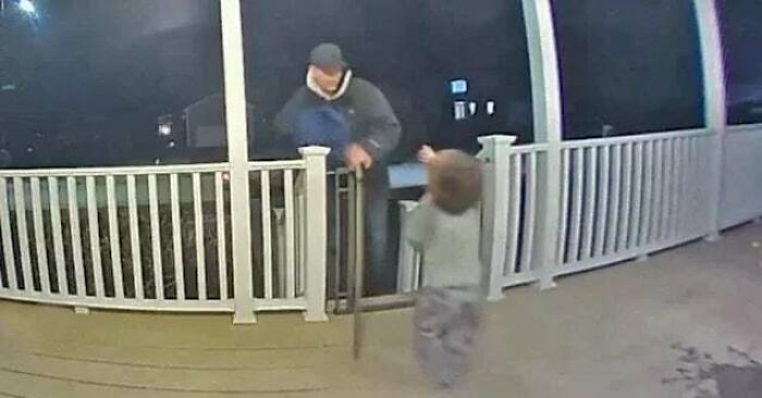 Man with cane and young child interacting on porch at night, capturing an inspiring moment of connection and kindness.