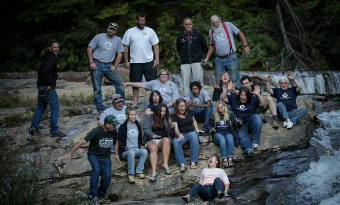 Group of people on rocky edge near rushing water, captured in a perfect picture moments before disaster struck rope broke.