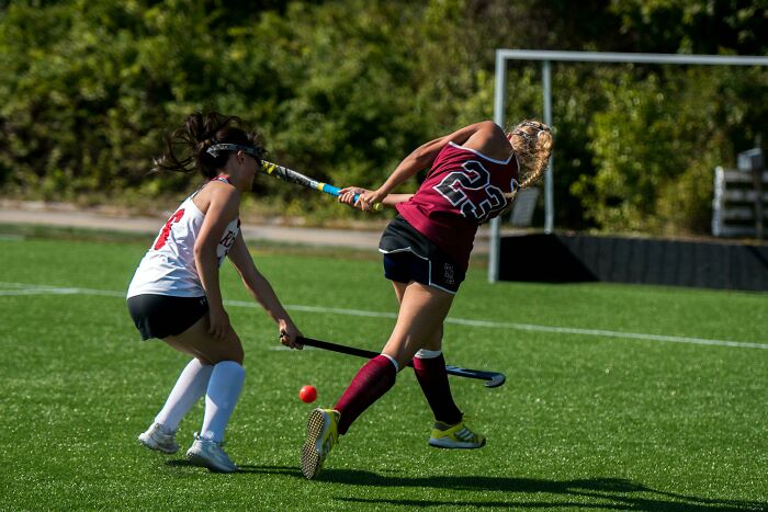 Two female field hockey players in action competing to hit the ball capturing the moment before the rope broke disaster.