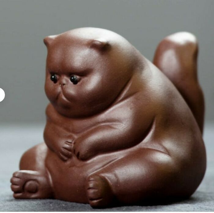 Brown ceramic figure of a chubby cat with large eyes, showcasing medieval cats art and human fascination with cats.