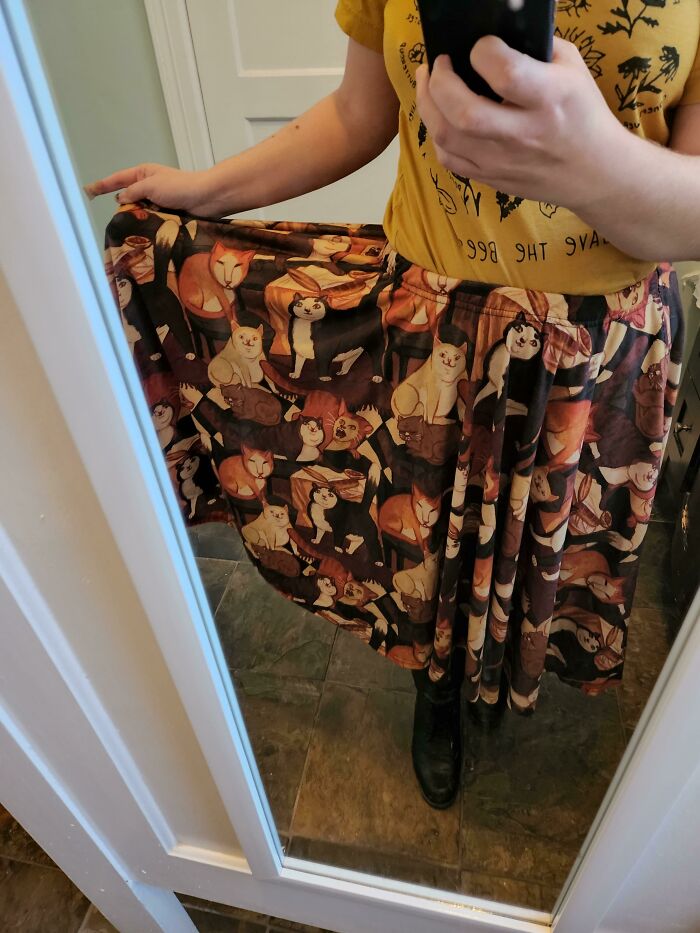 Person wearing a skirt decorated with medieval cats art, reflecting historical fascination with cats in clothing design.