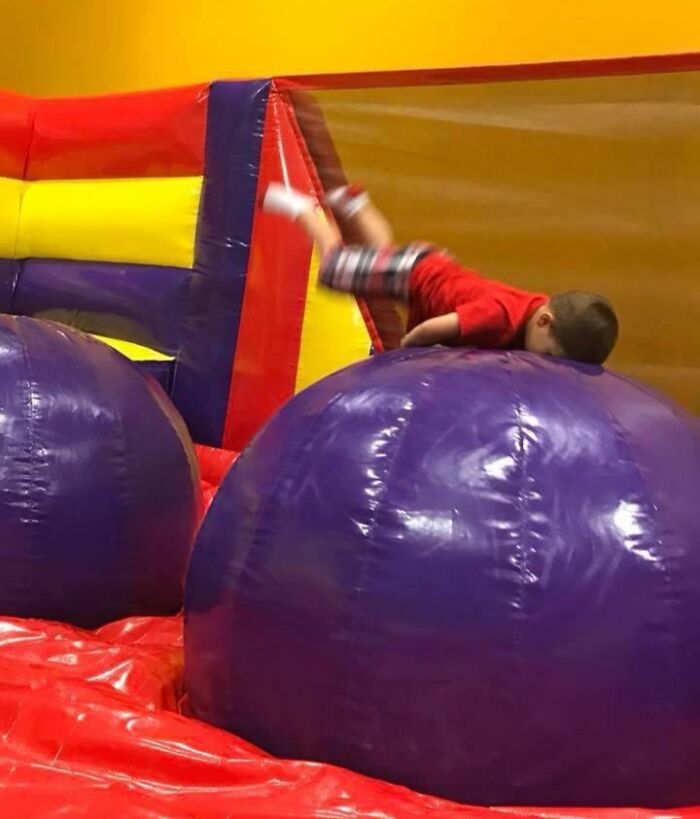 Young boy captured mid-fall on inflatable obstacle course, a perfect picture taken split seconds before disaster struck.