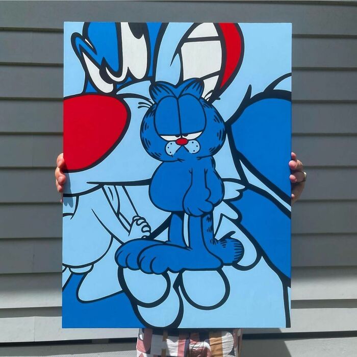 Pop mash artwork featuring a blue cartoon character mash-up held by a person outside against siding background.