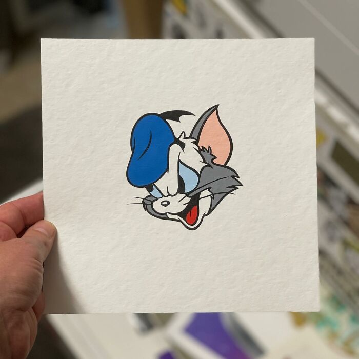 Hand holding paper with a pop culture and cartoon character mash-up artwork called pop mash featuring a hybrid face.