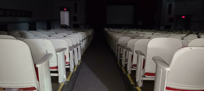 Empty dimly lit auditorium with worn seats, evoking a creepy and unsettling atmosphere related to jobs that should pay more.