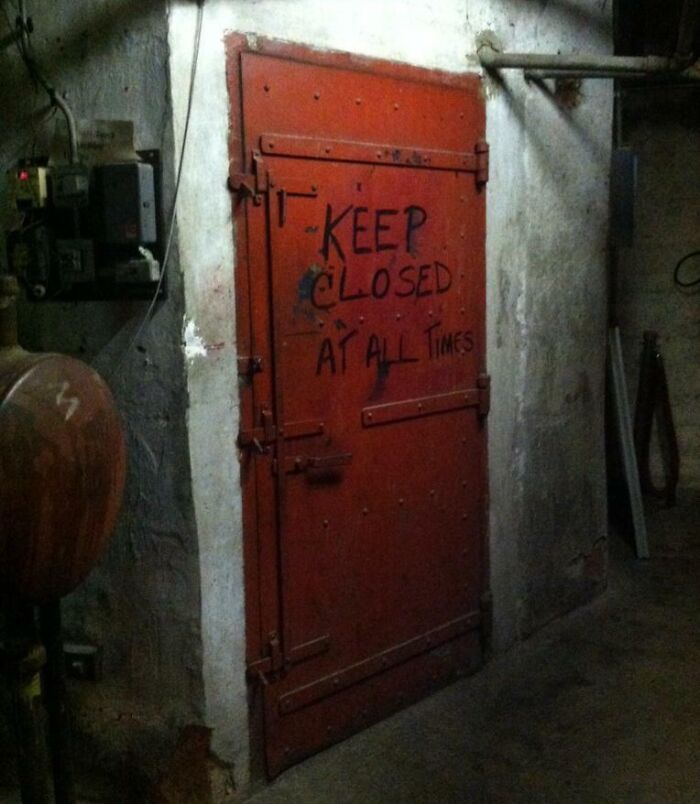 Dimly lit industrial door with warning sign seen in creepy and unsettling photos from jobs that should pay more workers.