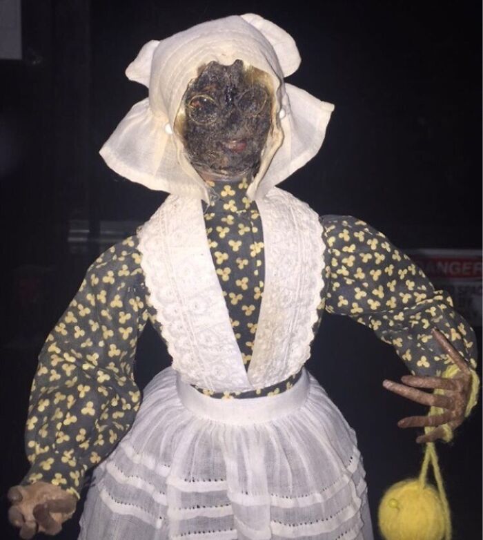 Creepy and unsettling worker photo showing a vintage doll mannequin in old-fashioned attire holding a yellow yarn ball.
