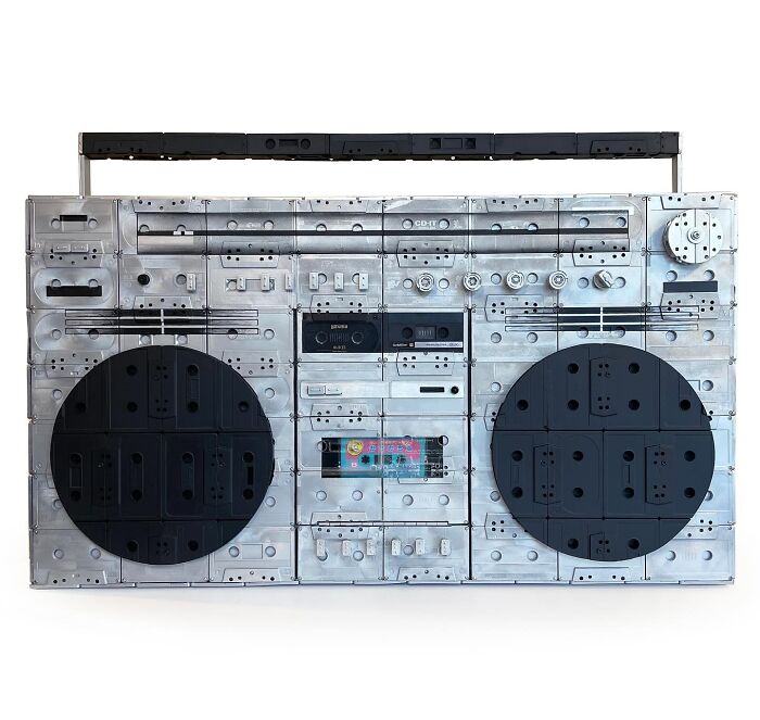 Boombox sculpture made from recycled cassette tapes, showcasing witty commentary on modern life through creative waste art.