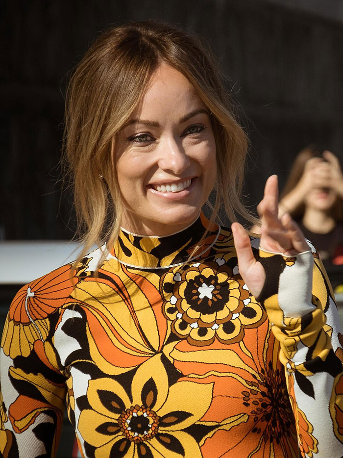 Olivia Wilde smiling and waving in a vibrant patterned outfit, showcasing her toned abs during New York Fashion Week. Olivia Wilde smiling and waving in a vibrant patterned outfit, showcasing her toned abs during New York Fashion Week.