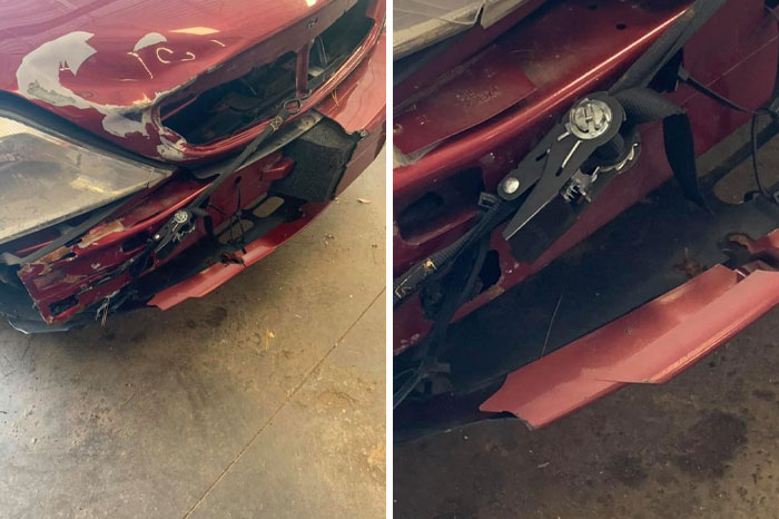 Damaged front end of a red car showing bent metal and missing bumper parts in a mechanic's workshop.