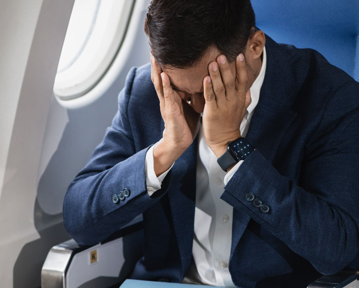 Passenger with head in hands experiencing distress on airplane during nightmare flight after seatmate incident before takeoff Passenger with head in hands experiencing distress on airplane during nightmare flight after seatmate incident before takeoff