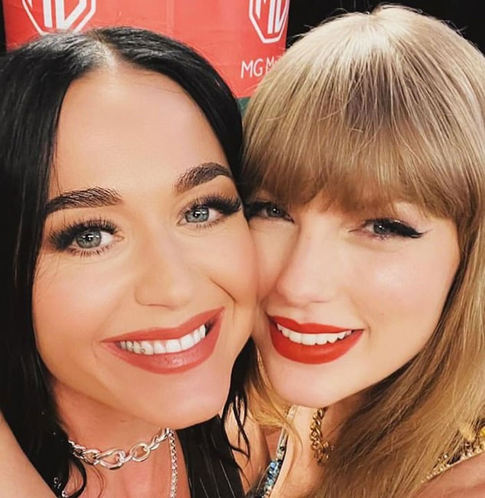 Close-up of two smiling women with makeup and red lipstick, related to Travis Kelce’s answer about Taylor Swift topic. Close-up of two smiling women with makeup and red lipstick, related to Travis Kelce’s answer about Taylor Swift topic.