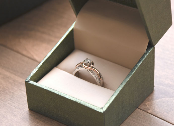 Engagement ring in a green box placed on a wooden surface, symbolizing moments that change everything after a glance at a phone.