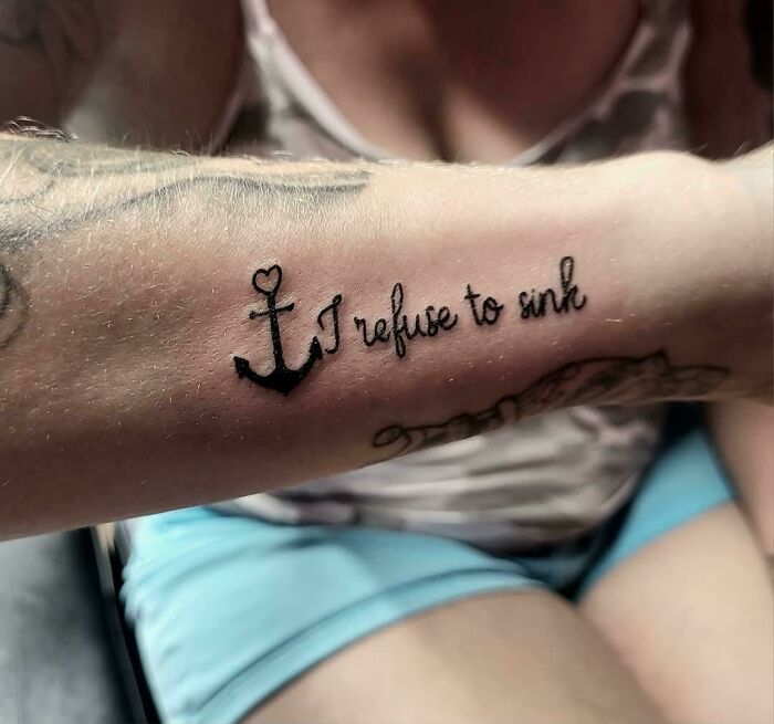 Close-up of a forearm tattoo featuring an anchor and the phrase I refuse to sink, showcasing unique client tattoo ideas.