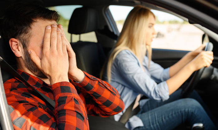 Man covering his face in distress while woman drives car, illustrating woman giving husband another chance lesson. Man covering his face in distress while woman drives car, illustrating woman giving husband another chance lesson.