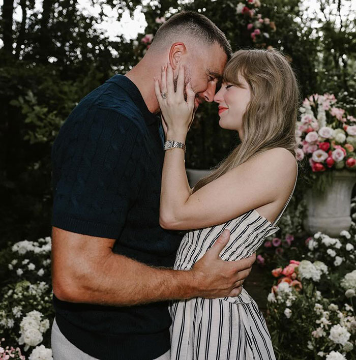 Travis Kelce and Taylor Swift embracing closely outdoors surrounded by flowers, highlighting Travis Kelce’s answer about Taylor Swift. Travis Kelce and Taylor Swift embracing closely outdoors surrounded by flowers, highlighting Travis Kelce’s answer about Taylor Swift.