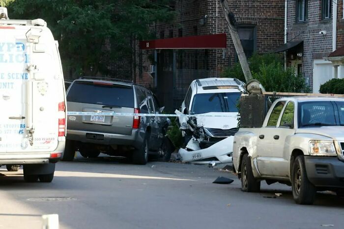 Damaged white car involved in maniac driver incident with NYPD police scene unit van and pickup truck nearby