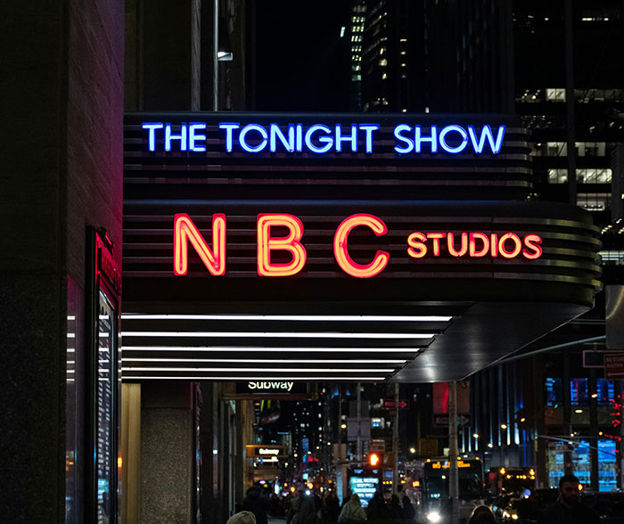 NBC Studios marquee for The Tonight Show illuminated at night, relating to Jimmy Fallon and show suspension news. NBC Studios marquee for The Tonight Show illuminated at night, relating to Jimmy Fallon and show suspension news.