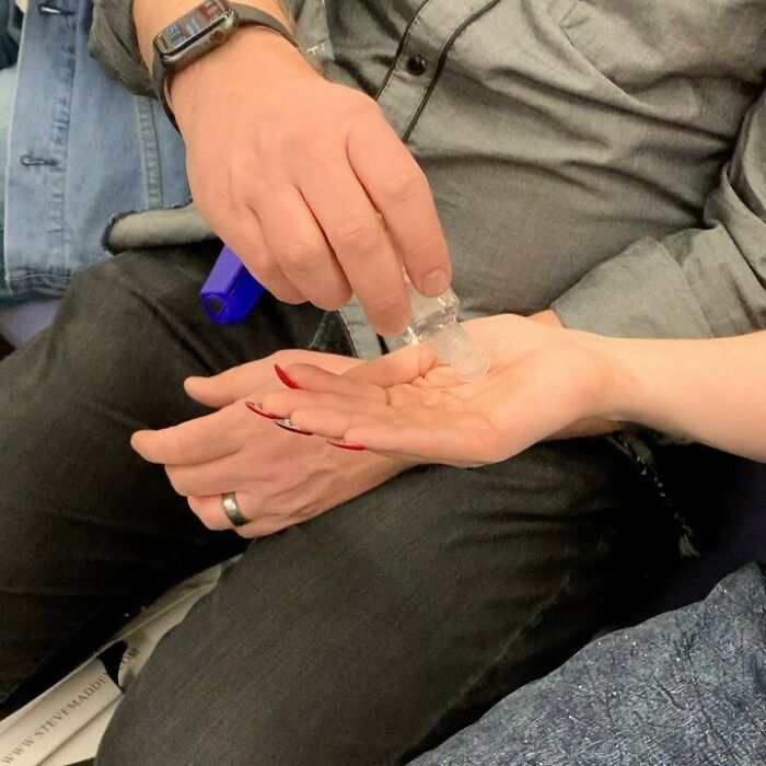 People taking the subway in New York using hand sanitizer in their hands while sitting closely together.