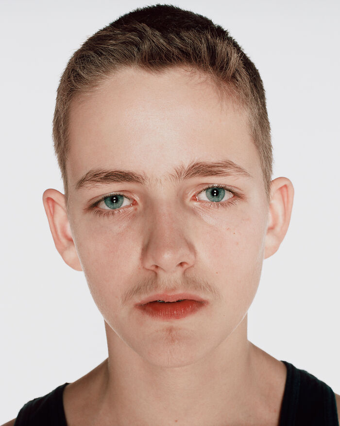 Close-up portrait of a young boxer with blue eyes and short hair, showing determination before his first match.