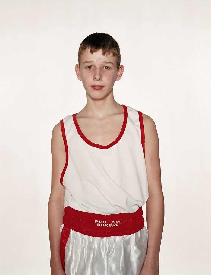 Young boxer wearing white and red boxing gear posing before a match in a powerful photograph of young boxers.