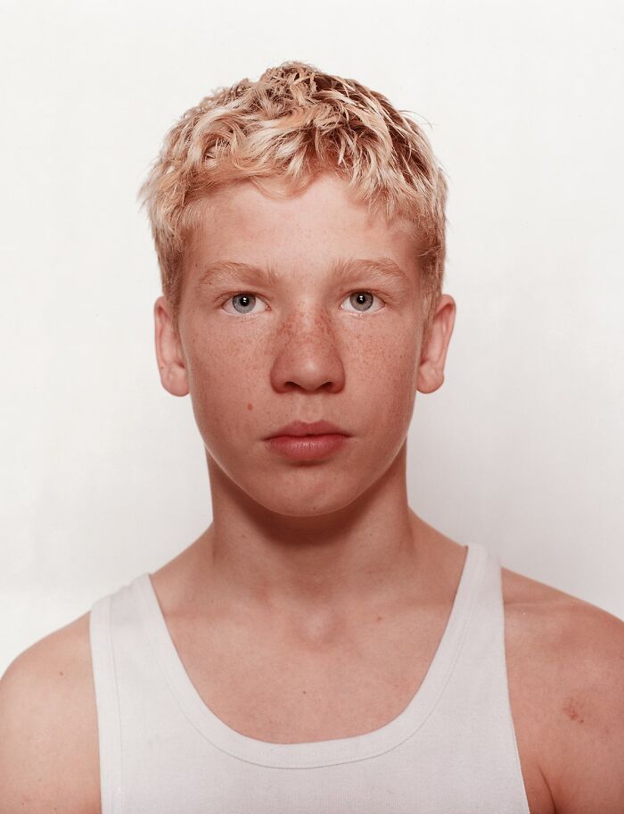 Young boxer with blonde hair and freckles wearing a white tank top, before his first match, showing determination and focus.