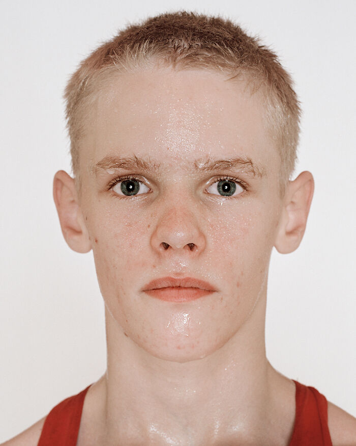 Close-up portrait of a young boxer with short hair wearing a red tank top before his first match showing determination.