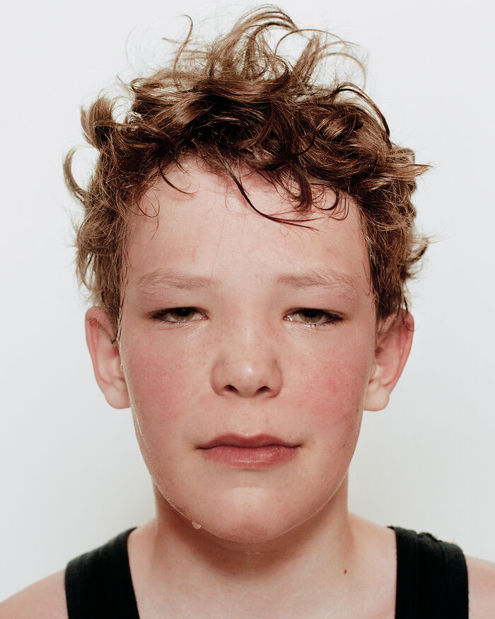 Close-up portrait of a young boxer with curly hair, showing calm confidence before their first match.