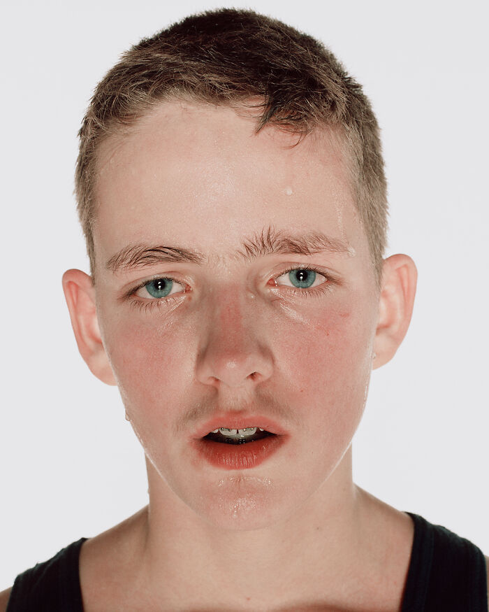 Close-up portrait of a young boxer with blue eyes and short hair, showing determination before his first match.