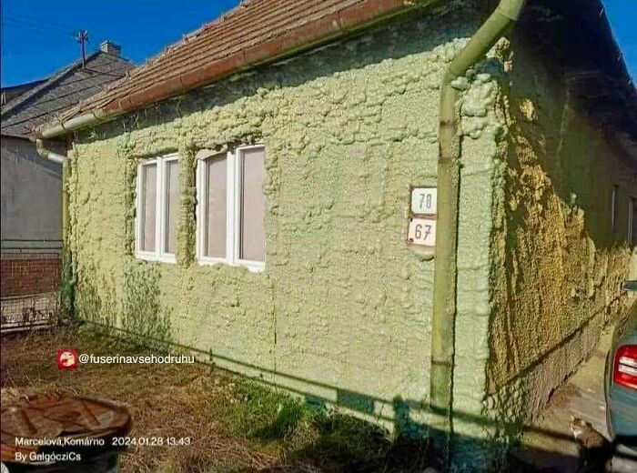 House covered in uneven, foamy construction material with rough, haphazard texture and unusual design features.