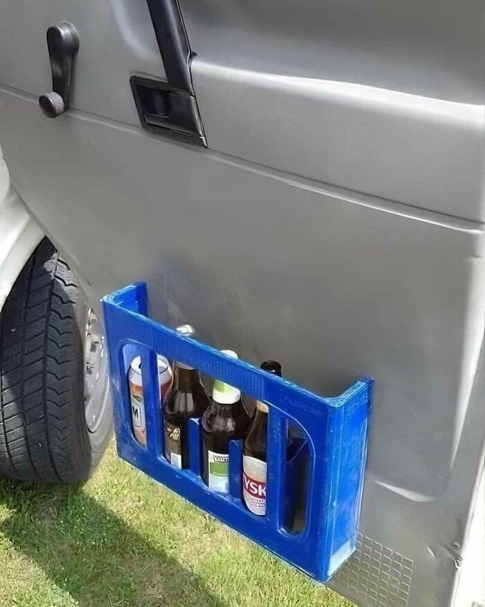 Blue plastic crate attached to a car door used as a makeshift holder for bottles and cans in an unusual design.