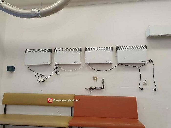 Four wall-mounted heaters with tangled cords above mismatched seating, showcasing unusual construction and design choices.