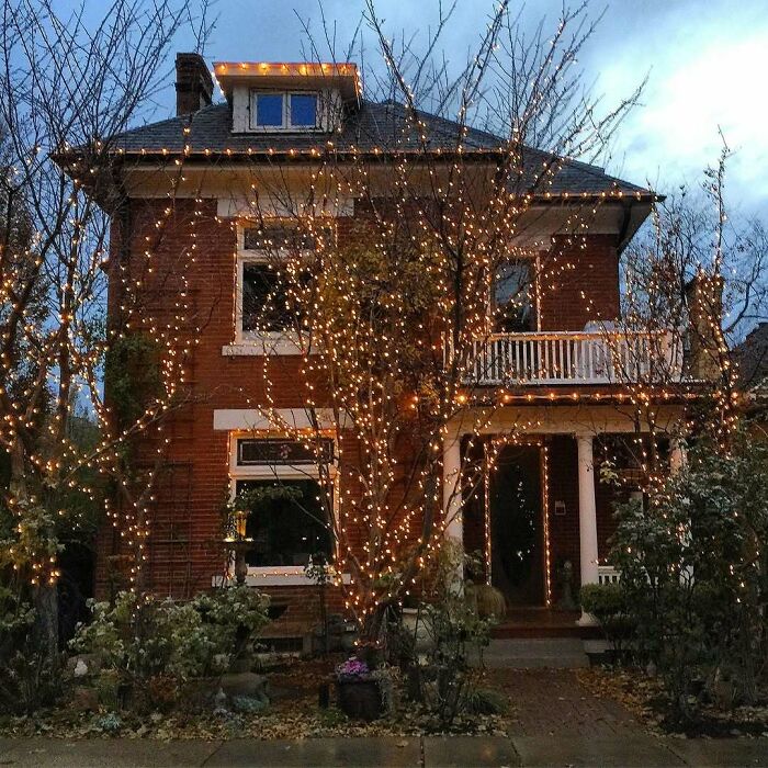 Old homes decorated with warm string lights on trees and porch, creating an inviting and adorable evening ambiance.